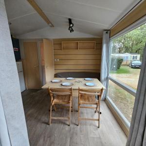 uma sala de jantar com uma mesa e cadeiras e uma janela em Mobil-Home – Puy du Fou (30 min) em La Boissière-de-Montaigu