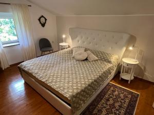 a bedroom with a large bed with two chairs and a window at Vila Stančič in Portorož