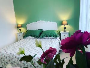 a bedroom with a bed with green walls and purple flowers at La casa di Luana sulla via Francigena in Monterosi