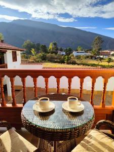 una mesa con 2 tazas de café en el balcón en Hotel las Palmas, en Villa de Leyva