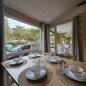 uma mesa com pratos e tigelas em cima em Mobil-Home – Puy du Fou (30 min) em La Boissière-de-Montaigu