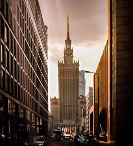 un grand bâtiment avec une tour d'horloge dans une ville dans l'établissement City View Apartment - Zgoda 13, à Varsovie