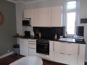a kitchen with white cabinets and a sink at Le P'tit Croissant in Bayeux