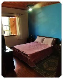 1 dormitorio con 1 cama con pared azul en Recanto GERMANO, en Campos do Jordão