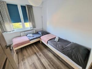 a bedroom with two beds and two windows at Apartament na wynajem in Nowy Targ
