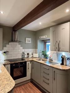 uma cozinha com armários brancos e uma bancada em Weather Hill Cottage, Hebden Bridge em Hebden Bridge