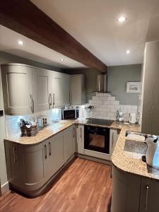 a large kitchen with white cabinets and wooden floors at Weather Hill Cottage, Hebden Bridge in Hebden Bridge