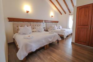 1 dormitorio con 2 camas, sábanas blancas y suelo de madera. en Hotel las Palmas, en Villa de Leyva