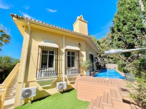 a yellow house with a deck and a swimming pool at Villa Mijas Playa in Málaga