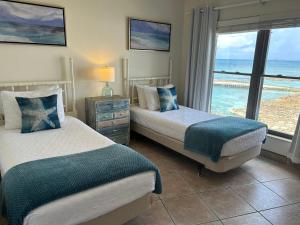 two beds in a room with a view of the ocean at Georgetown Villas #201 in George Town