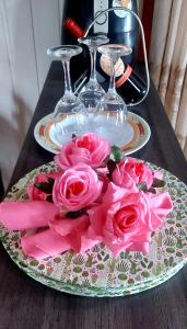 a plate with pink roses on a table with glasses at Casa em Canela RS in Canela