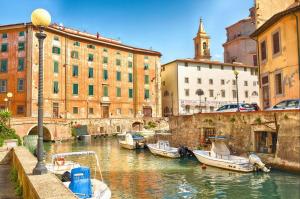 a group of boats docked in a canal with buildings at Japandi, Appartamento Zona Porto Mediceo Livorno in Livorno