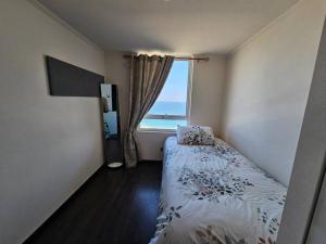 1 dormitorio con 1 cama y vistas al océano en departamento frente a la playa, en Iquique
