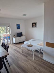 ein weißes Wohnzimmer mit einem Tisch und einem Bett in der Unterkunft Villa Roing S in Stanići