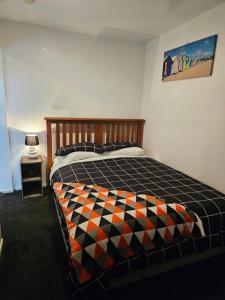 a bedroom with a bed with a checkered blanket at Marg's on the Corner in Kumara