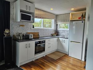 a kitchen with white cabinets and a white refrigerator at Marg's on the Corner in Kumara