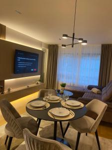 - un salon avec une table, des chaises et une télévision dans l'établissement Miyaki Apartments - BJELASNICA, à Bjelašnica