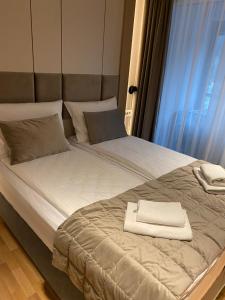 - un grand lit avec une serviette blanche dans l'établissement Miyaki Apartments - BJELASNICA, à Bjelašnica