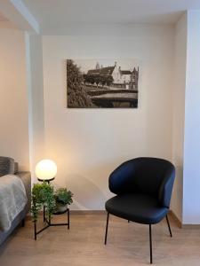 ein schwarzer Stuhl in einem Zimmer mit einem Bild an der Wand in der Unterkunft Huyze Ter Vaete in Lo-Reninge