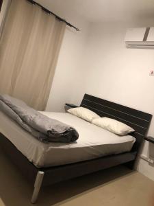 Bett mit schwarzem Kopfteil sowie weißer Bettwäsche und Kissen in der Unterkunft Rayon Bleu C2 in Flic-en-Flac