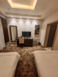 una camera d'albergo con due letti e una televisione di فندق دان البلاتيني a Medina