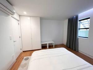 a white bedroom with a large bed and a window at New Cozy Modern Minimalist Stay in Brooklyn at Rem-Casa in Brooklyn