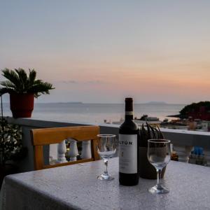 una botella de vino sentada en una mesa con dos copas en Sea Breeze Rooms, en Himare