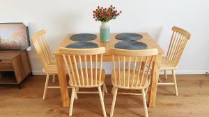 a wooden table with four chairs and a vase with flowers at HADLOW 带花园的整套联排别墅 in Auckland