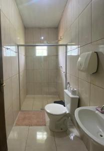 a bathroom with a shower and a toilet and a sink at Pousada Nikimba in São Roque de Minas