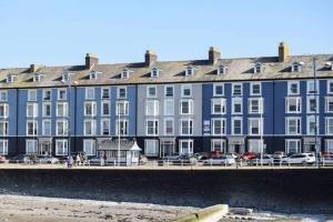 a large blue building next to a body of water at Swn Y Mor 4 Aberystwyth in Aberystwyth