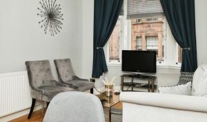 a living room with two chairs and a television at Modern Glasgow City Centre Apartment in Glasgow