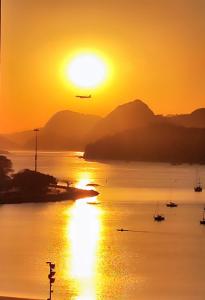 una puesta de sol sobre un cuerpo de agua con un avión en Aragão Botafogo Studio, en Río de Janeiro