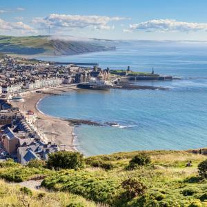 a view of a beach with a city and the ocean at Luxury Seaside accommodation, Swn Y Mor in Aberystwyth