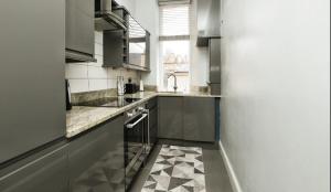 a kitchen with stainless steel appliances and a checkered floor at Modern Glasgow City Centre Apartment in Glasgow