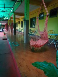 una hamaca roja colgada de un edificio con mesas y sillas en RESIDENCIAL LOS AMIGOS en Puerto Iguazú