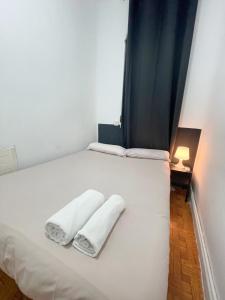uma cama branca com duas toalhas brancas em Toledo habitaciones em Madri
