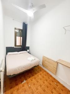 um pequeno quarto com uma cama e piso em madeira em Toledo habitaciones em Madri