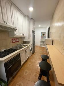 uma cozinha com armários brancos e um lavatório e dois bancos em Toledo habitaciones em Madri