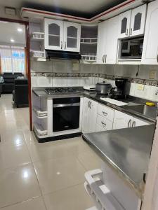 uma cozinha com armários brancos e um forno com placa de fogão em Casa Turistica HL em Armênia