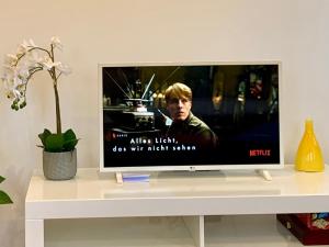 telewizor z płaskim ekranem siedzący na białym stole w obiekcie Heimat - Apartment in der Altstadt Fulda l 47 qm l Netflix l WLAN l Wohnzimmer l Schlafzimmer l Küche l Bad w mieście Fulda