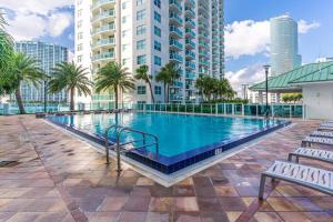 a large swimming pool with palm trees and buildings at Duplex 2BR in Miami