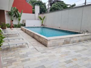 a swimming pool on a patio with chairs and a building at Studio próximo Avenida Paulista in Sao Paulo