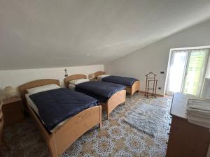 a bedroom with three beds and a window at CA' EDDA APPARTAMENTO GIULIA in Brentonico