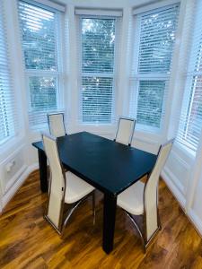a black table and chairs in a room with windows at Newly refurbished two bedrooms flat in St. Leonards