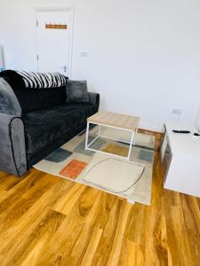 Sala de estar con sofá negro y mesa de centro en Newly refurbished two bedrooms flat en St. Leonards