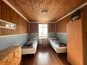 Duas camas num quarto com paredes de madeira em Tærgesen Guesthouse em Reydarfjördur