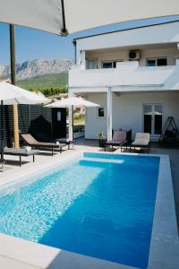 Villa con piscina azul y sombrillas en AMI en Solin
