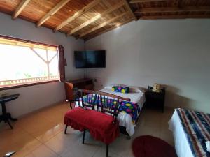 1 dormitorio con 2 camas, TV y ventana en Alojamiento en Jardin Cabaña las Aguilas en Jardin
