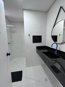 a bathroom with a shower and a sink and a mirror at Frente ao mar Pitangueiras - 3 suítes in Guarujá