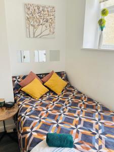 een slaapkamer met een bed met gele en oranje kussens bij Studio flat in Shipley Central in Shipley